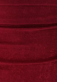 Bordo prilagođeni materijal s rebrastom teksturom i horizontalnim šavovima, stvarajući slojeviti efekt. Mekani, rastezljivi materijal.