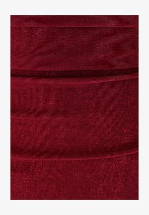 Burgundin värinen, tiukasti istuva kangas, jossa on uurrettu pinta ja vaakasaumat, luoden kerroksellista vaikutelmaa. Pehmeä ja joustava materiaali.