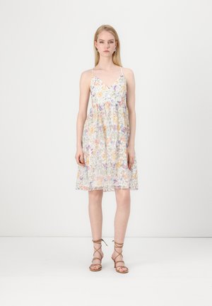 Robe florale avec un décolleté en V, des bretelles spaghetti réglables et un ourlet évasé. Douces couleurs pastel sur un fond clair. Portée avec des sandales à lanières.