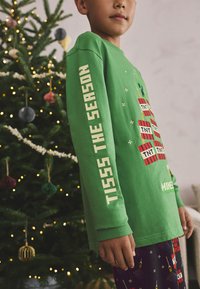 Green long-sleeve shirt with "TISSS THE SEASON" text on sleeve, featuring Minecraft-themed design with colorful blocks and patterns.