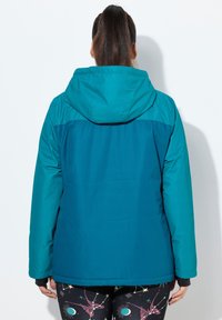 Tealfärgad isolerad jacka med huva, med en tvåtonslösning. Slät yta, långa ärmar och en något figursydd form.