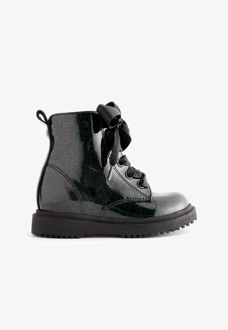 Bottine noire brillante avec paillettes, semelle épaisse et larges lacets noirs en ruban noués en boucle sur le côté.