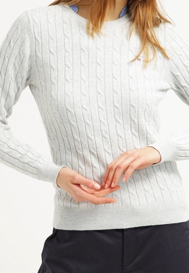 Maglione grigio chiaro con motivo a treccia a costine, scollo rotondo e polsini e orlo aderenti. Presenta un sottile logo del brand sul petto.