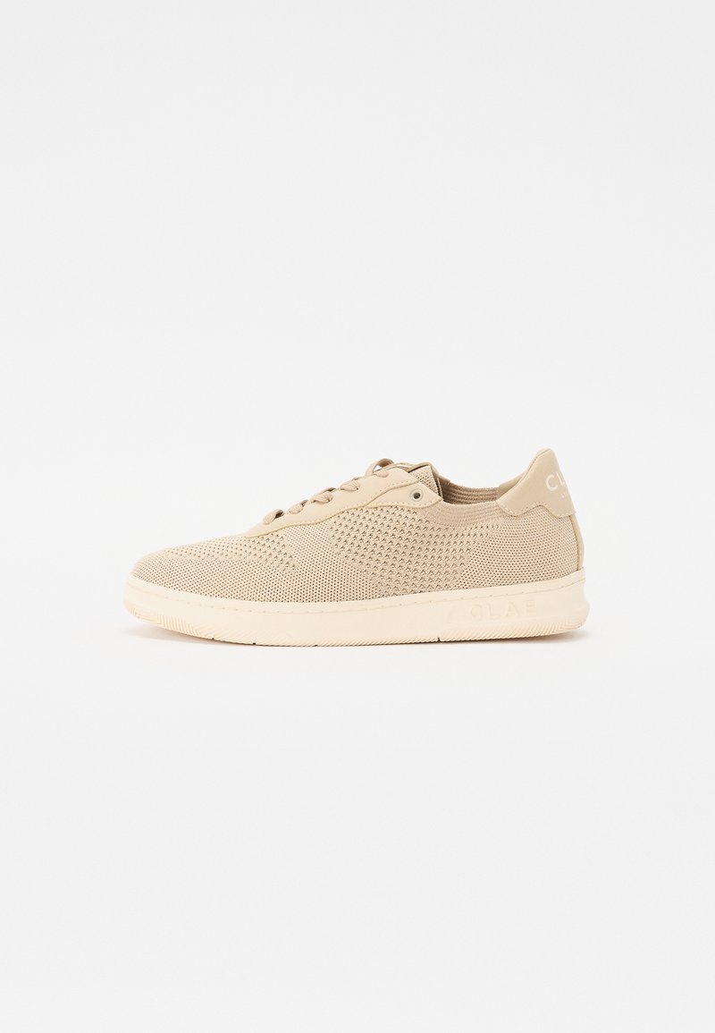 Sneaker beige realizzato in materiale a rete traspirante, con un motivo testurizzato, chiusura con lacci e suola in gomma con un branding discreto.