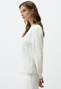 Witte textuur sweatshirt met een geborduurd patroon met verhoogde geometrische ontwerpen, ronde halslijn en geribbelde manchetten.