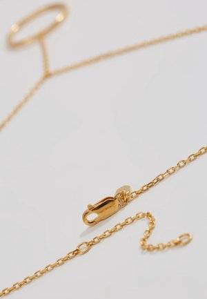 Collier chaîne en or avec fermoir homard et segment d'extension réglable sur fond blanc.