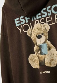 Brauner Hoodie mit einem bedruckten Teddybär, der eine blaue Tasse hält, und dem Text "ESPRESSO YOURSELF" in Hellblau und Beige.