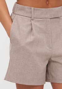 Shorts dintr-un amestec de in bej, cu un talie croită, având două buzunare laterale și o textură subtilă, care ajung la înălțimea medie a coapselor.