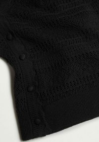 Tissu tricoté noir présentant un motif géométrique texturé avec des boutons recouverts de tissu sur un bord.