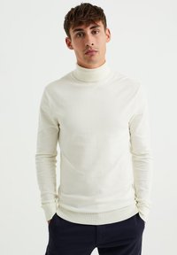 Cremefarbener Rollkragenpullover aus einem weichen, glatten Stoff. Eng anliegende Ärmel und gerippte Bündchen, mit hohem Kragen und minimalistischen Design.
