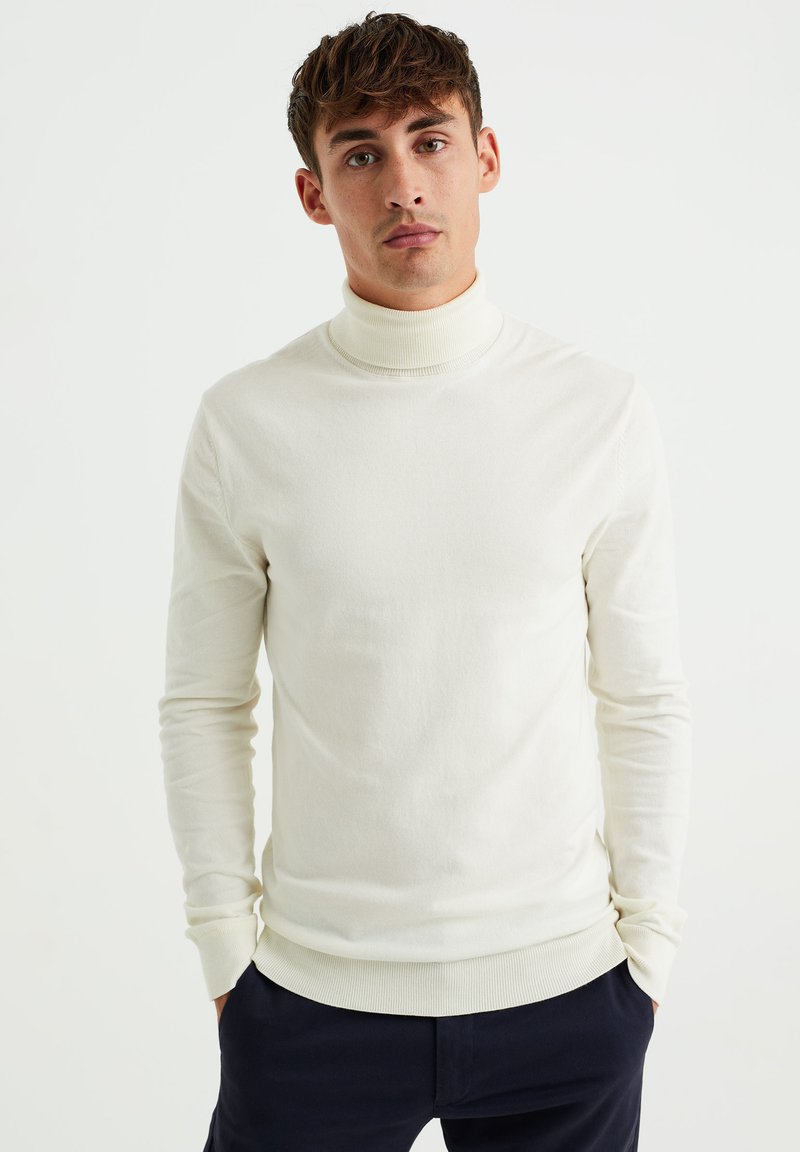 Cremefarbener Rollkragenpullover aus einem weichen, glatten Stoff. Eng anliegende Ärmel und gerippte Bündchen, mit hohem Kragen und minimalistischen Design.