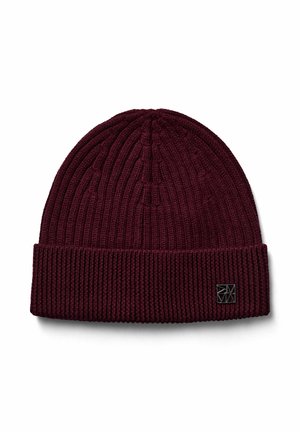Burgundy ribbed knit beanie with folded cuff and small black metal logo tag on cuff front right side.
