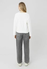 Chandail blanc texturé à manches longues, assorti à un jean large gris taille haute. Baskets avec une couleur crème à la base.