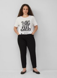 Witte katoen t-shirt met zwart grafisch tekst en bloemontwerpen, gecombineerd met zwarte katoen broek en zwarte versierde ballerina's.