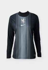 Long-sleeve shirt in black and gray with vertical stripes, featuring a lion emblem and Nike logo on the chest. Smooth texture, athletic fit.