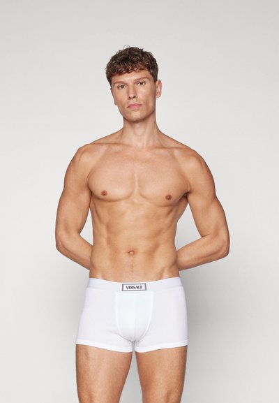 Boxeri din bumbac alb, cu o potrivire strânsă și un talie elastică, având un eticheta cu "VERSACE" brodată pe față.