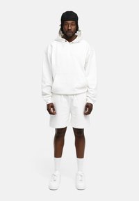 White hoodie with a front pocket and drawstring, paired with matching shorts. Complete with white sneakers and ankle socks.