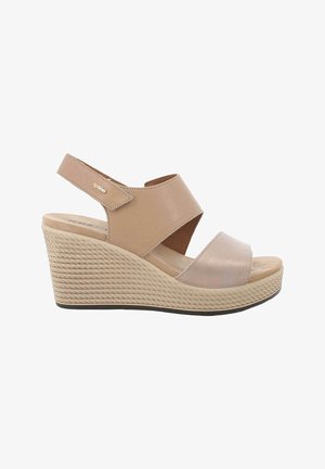 Sandalo beige con zeppa, suola piatta testurizzata, due ampie cinghie incrociate e cinturino posteriore regolabile con chiusura in Velcro.