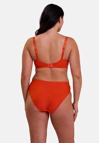 Set di reggiseno arancione e slip bikini a vita alta. Tessuto morbido con bordi ondulati e spalline regolabili, progettato per il comfort.