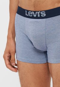 Boxers en tricot bleu avec un motif texturé, dotés d'une taille bleu foncé avec le logo Levi's en lettres bleu clair et blanches.