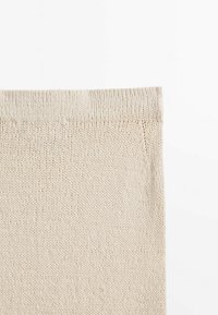 Beige gebreide stof met een zachte textuur, voorzien van een omgeslagen zoom aan de bovenkant en een eenvoudig, uniform ontwerp.