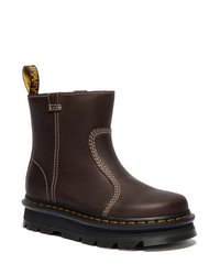 Bruine leren enkelboot met contrasterende stiksels en een trekflap. Dikke zwarte rubberen zool met een robuust profiel en een oranje accent rond de basis.