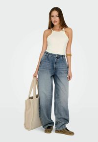 Ljusblå jeans med vida ben, krämfärgad linne, beige väska och sneakers med leopardmönster. Släta ytor, avslappnad passform och avslappnad stil.