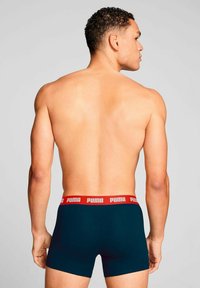PUMA men's boxer briefs, featuring a dark blue fabric, elastic red waistband with white letters, and a snug fit design.