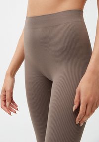 Geribbelde bruine legging met een hoge tailleband, voorzien van een zachte textuur en een aansluitend ontwerp dat de beenvorm accentueert.