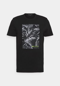 Camiseta de manga corta negra con estampado de hojas tropicales en blanco y pequeño logo verde de Michael Kors con texto en el centro frontal.