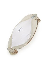 Beige Kipling-pung med åben lynlås, der viser et tomt hvidt indre og et mærket stoflabel indeni.