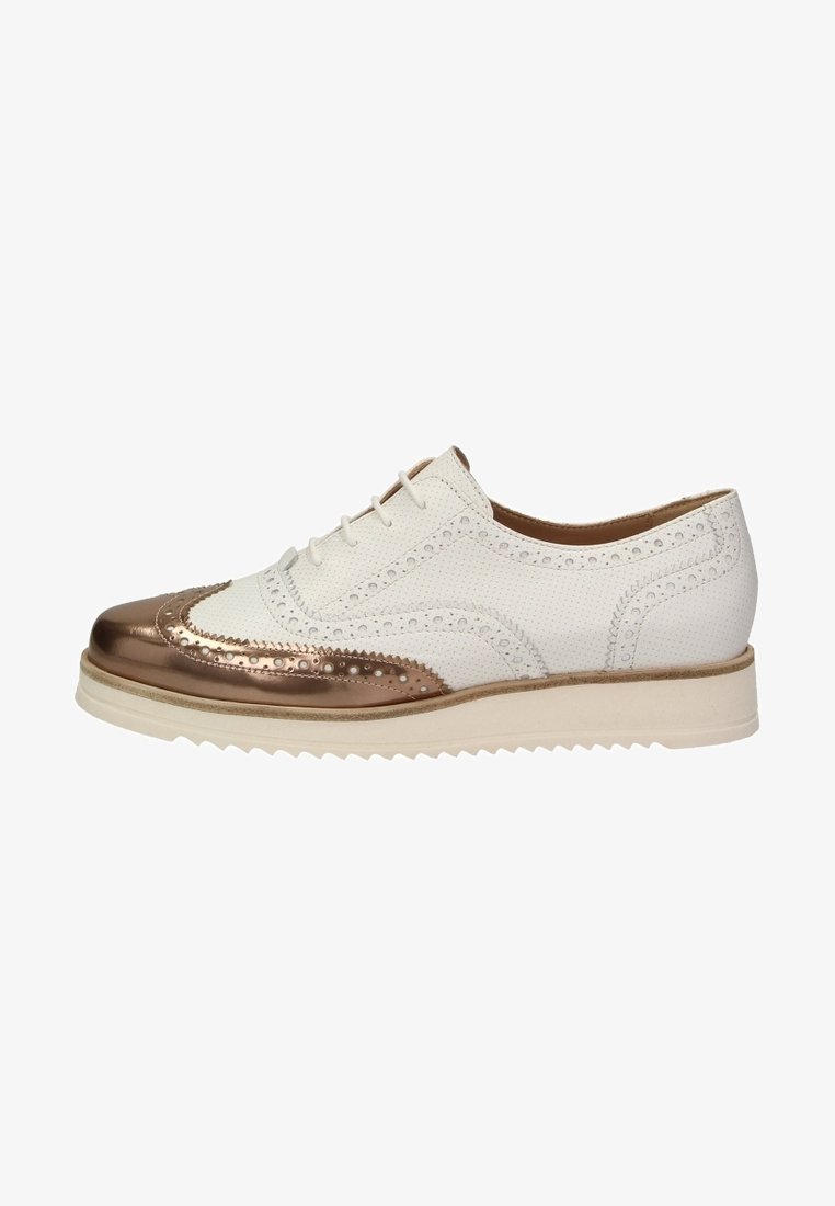 Chaussure brogue en cuir blanc perforé avec embout métallique bronze, semelle crème, et détails décoratifs perforés, vue de côté.