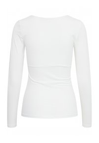 Fehér, hosszú ujjú felső, kerek nyakkivágással, testhez simuló fazonnal és sima anyagból. Derékrészen varrási részletek a formázás érdekében.