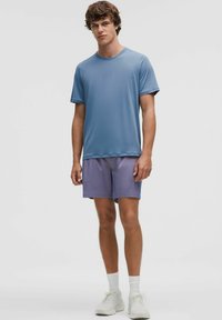 Herretoj til mænd: en kortærmet lyseblå svedtransporterende skjorte, der matches med lilla shorts. Har en afslappet pasform og letvægts stof.