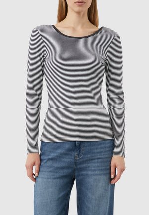 Langarmshirt mit gestreiftem Schwarz-Weißen Muster, Rundhalsausschnitt, figurbetonter Silhouette und weicher Stofftextur. Getragen mit blauen Jeans.