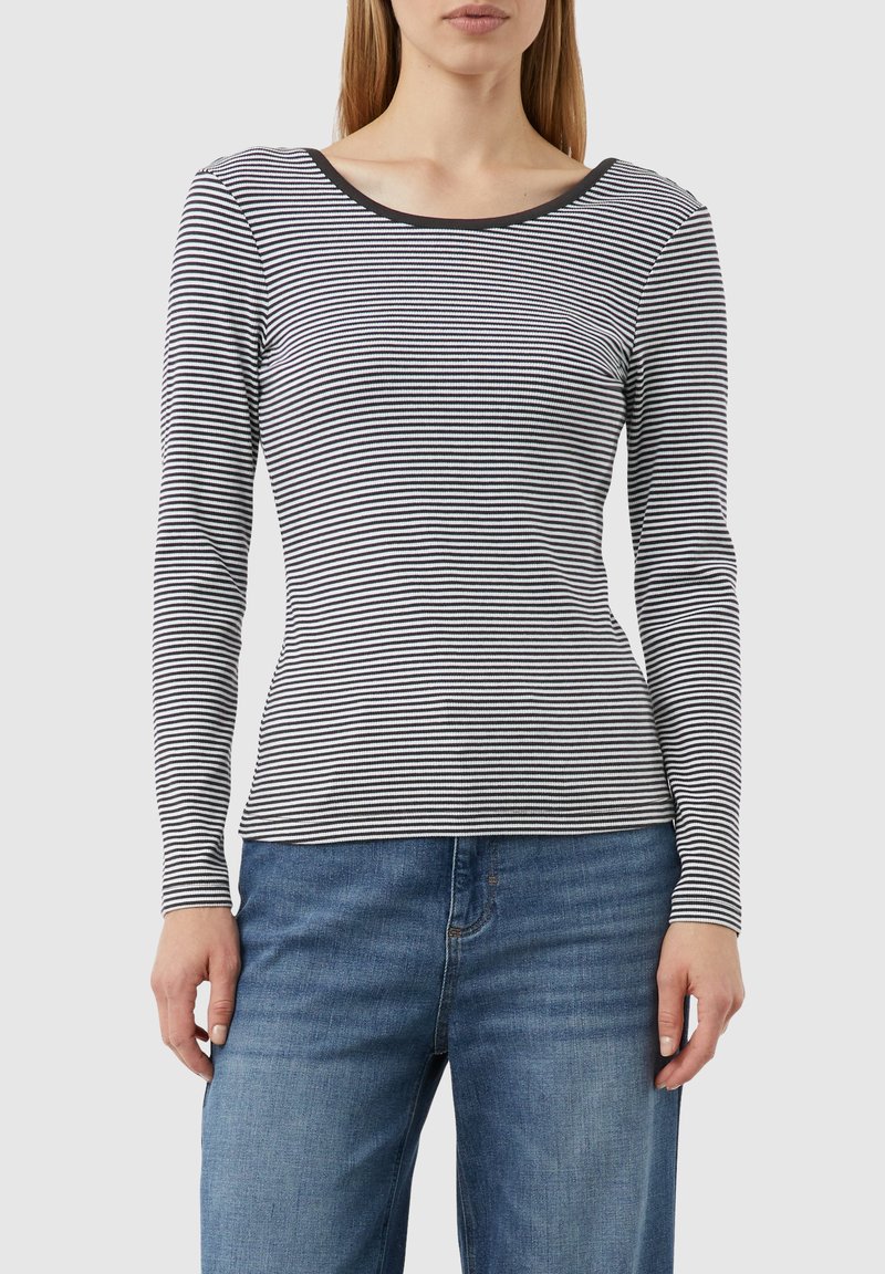 Langarmshirt mit gestreiftem Schwarz-Weißen Muster, Rundhalsausschnitt, figurbetonter Silhouette und weicher Stofftextur. Getragen mit blauen Jeans.