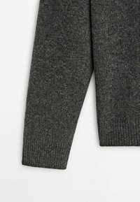 Manche de pull en maille gris foncé avec bord-côtes sur fond blanc, montrant la texture et les détails du tissu.