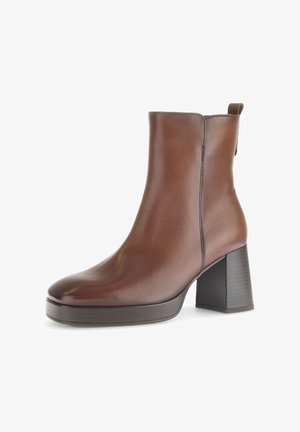 Brązowy skórzany botek do kostki z okrągłym noskiem, wysokim słupkowym obcasem oraz teksturowaną podeszwą na platformie. Posiada bezszwowy design z minimalną ilością szwów.