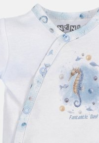 Witte katoenen romper met een lichtblauwe rand en drukknoopjes, voorzien van een zeepaard illustratie en kleurrijke cirkels, met de tekst "Fantastische Dag!"