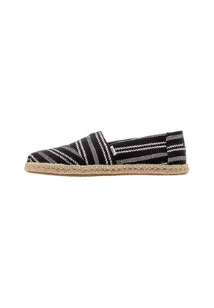Black and white striped espadrille with a woven textile upper, closed toe, jute midsole, and flat rubber sole.