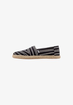 Black and white striped espadrille with a woven textile upper, closed toe, jute midsole, and flat rubber sole.