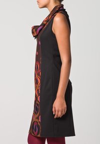 Robe noire sans manches avec une écharpe colorée à motifs. L'écharpe présente des motifs circulaires violets, oranges et rouges sur un fond marron.