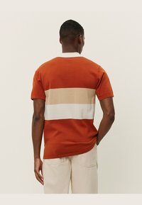 Kortermet skjorte med horisontale striper i terrakotta, beige og hvit. Laget av bomull, med rund hals og vanlig passform.