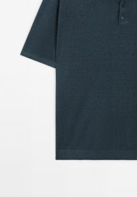Tmavě modré polo tričko s krátkým rukávem vyrobené z texturované látky, s tříknoflíkovým zapínáním a rovým lemem na spodní části.