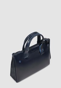 Bolso de cuero azul marino con dos asas, cierre de cremallera y costuras contrastantes en azul. Presenta una forma rectangular elegante y una sutil marca.