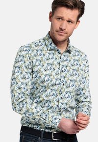 Een button-up shirt met een bloemenpatroon op een witte achtergrond met groene en blauwe bladeren. Lange mouwen en een puntige kraag, gemaakt van lichtgewicht stof.