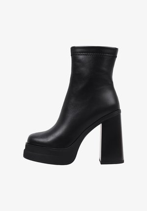 Bottine noire en cuir avec talon haut épais et semelle compensée, texture lisse et bord supérieur orné d'une simple couture.