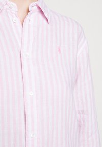 Ljusrosa och vitrandig linne skjorta med knäppning krage och en liten broderad logotyp på bröstet. Texturerad, avslappnad design.