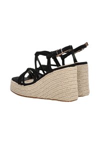 Sandalias de cuña de ante negro con plataforma de yute trenzado, que presentan tiras entrecruzadas y una correa adjustable en el tobillo. Parte inferior de corcho texturizado.