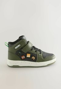 Scarpa da ginnastica alta verde oliva con accenti neri, caratterizzata da una suola intermedia bianca screziata e tre toppe decorative a tema Minecraft.